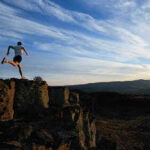A man is running on top of a rocky cliff.