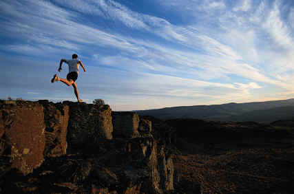 A man is running on top of a rocky cliff.