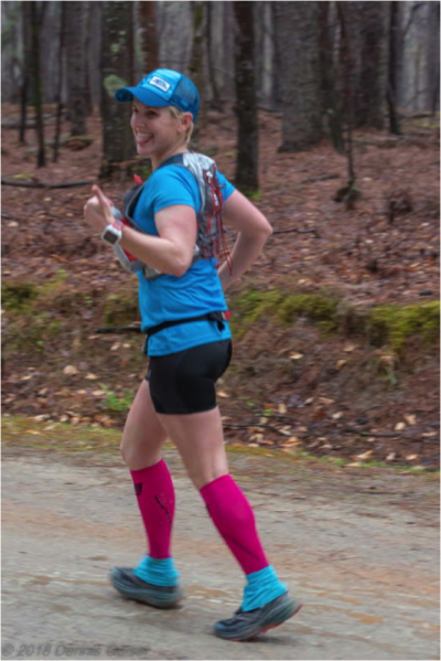 A woman is running in the woods.