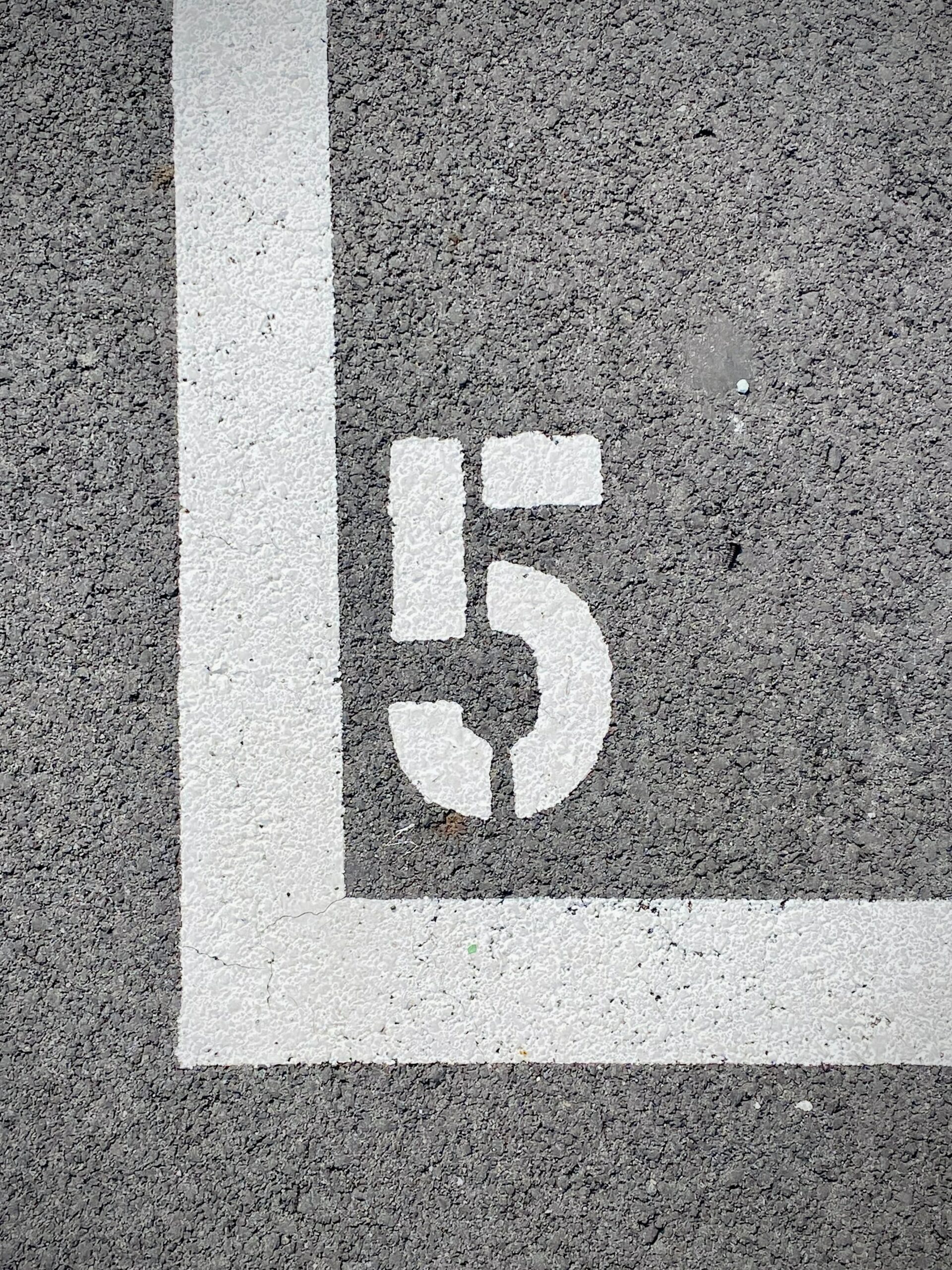 A white number five painted on a concrete road.