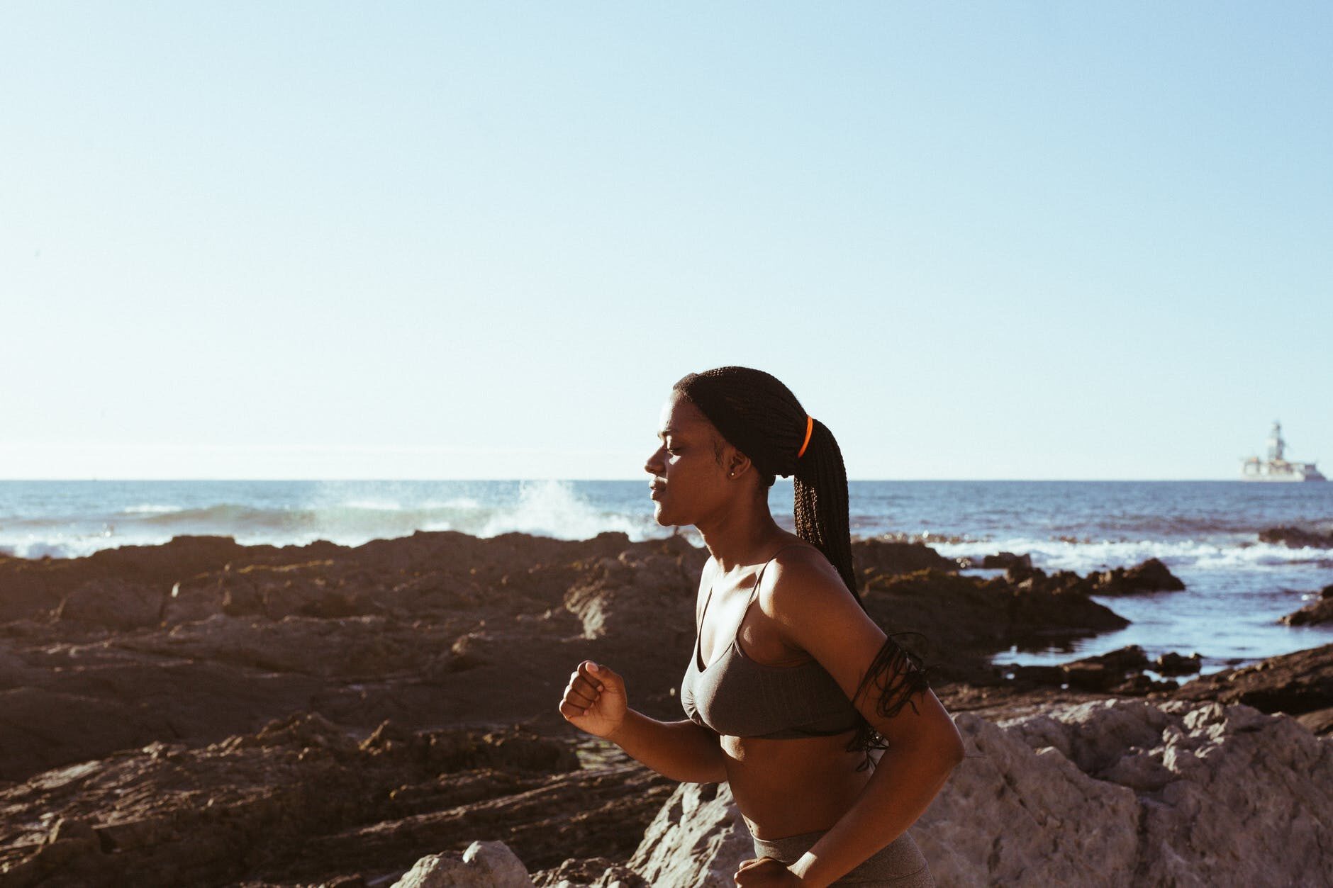 A woman runs along the shoreline during her DIY training camp. 