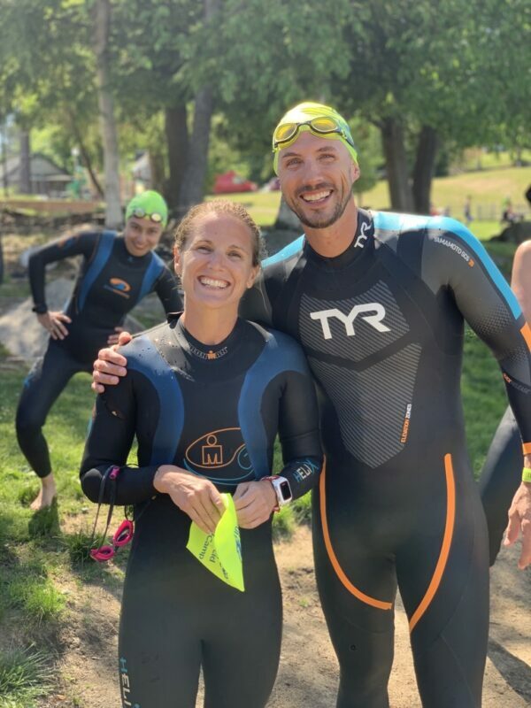 Two people in wetsuits posing for a photo.