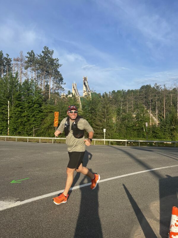 A man running on a road with trees in the background.