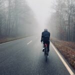 A man riding a bicycle on a foggy road.