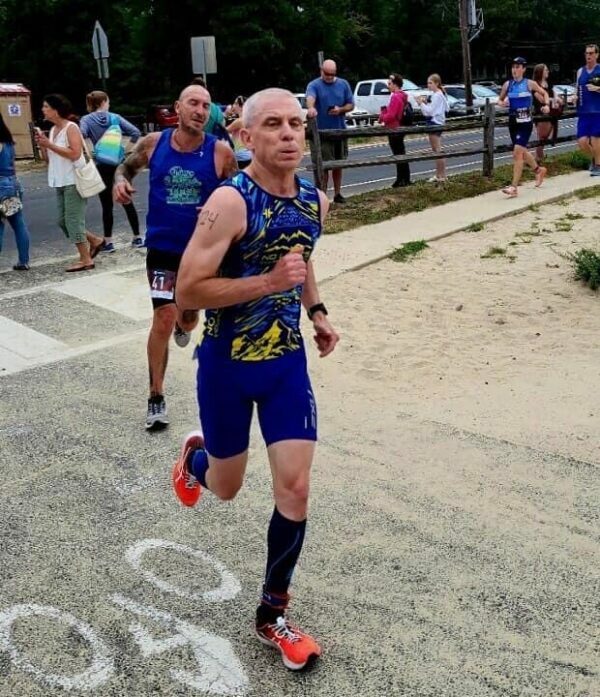 A man in a blue trisuit running in a race.