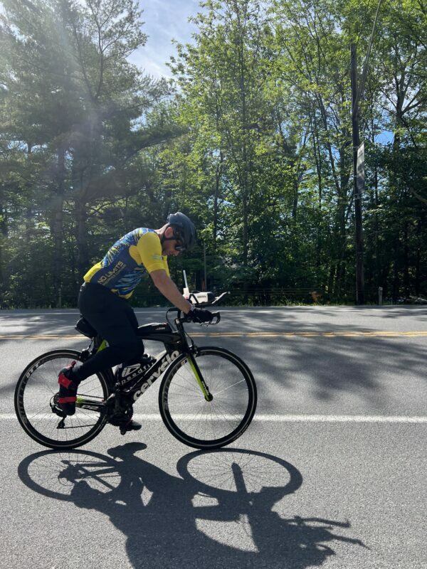 A man riding a bike on a road with trees in the background.