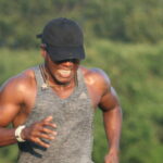 A man in a hat is running in a park.