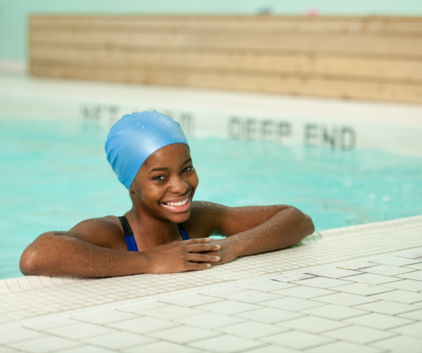 A young girl wearing a blue swim cap in a swimming pool.