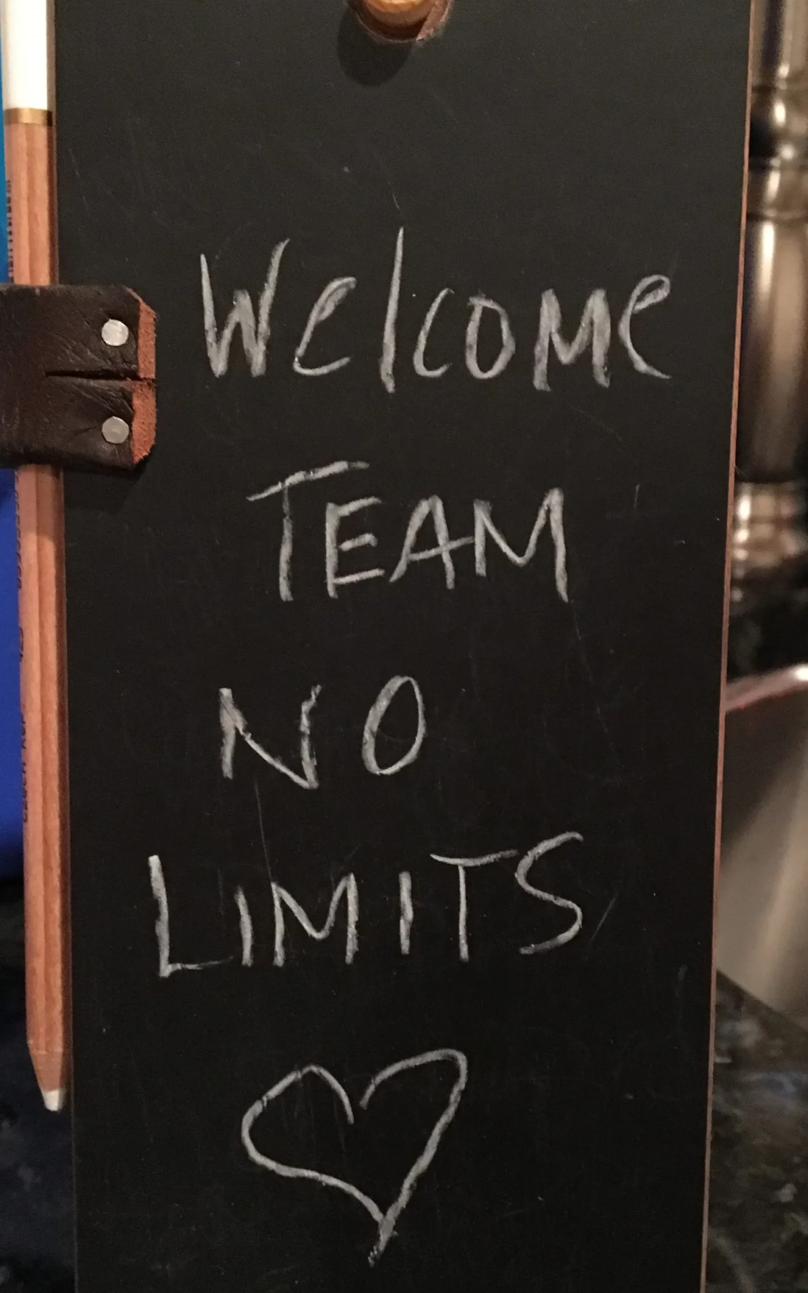 A chalkboard sign that says welcome team no limits.