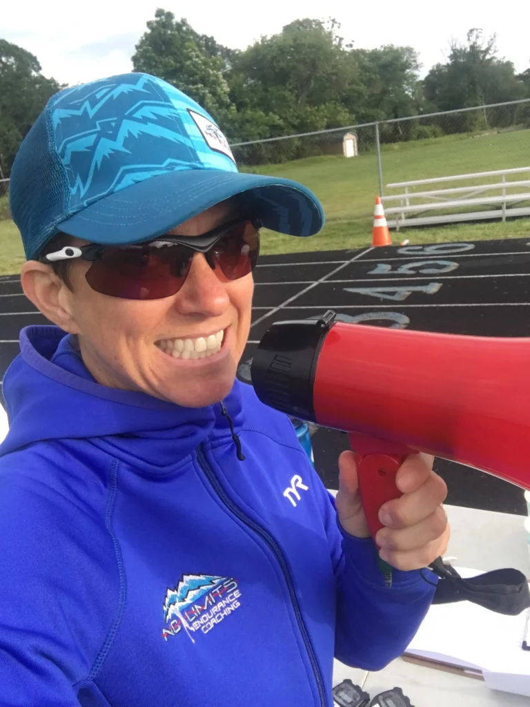 A woman holding a megaphone in front of a track.