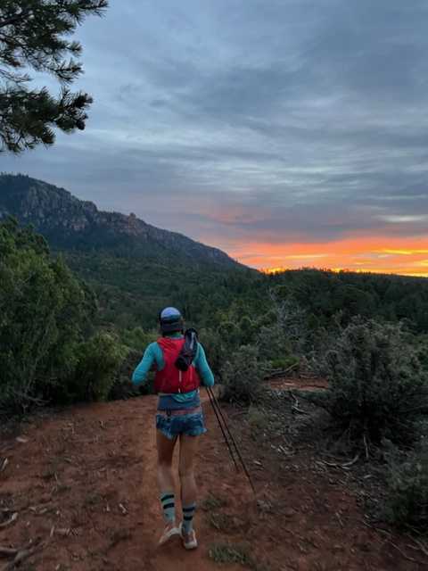 A woman hiking on a trail at sunset.