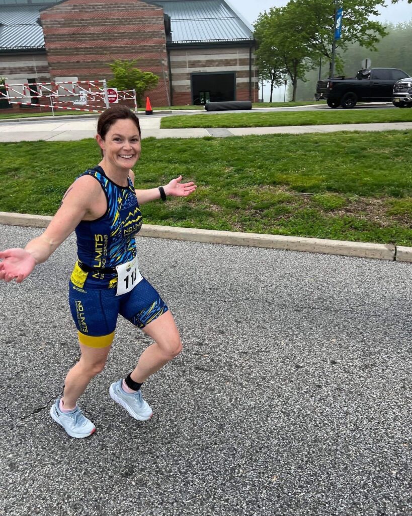 A woman in a blue and yellow trisuit running down the road.
