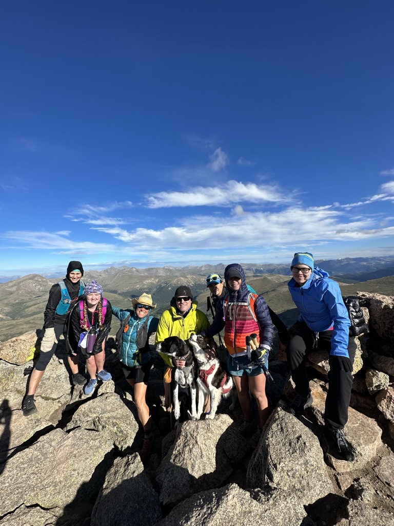A group of people on top of a mountain with a dog.